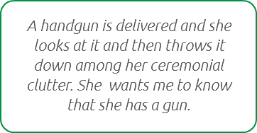 A handgun is delivered and she looks at it and then throws it down among her ceremonial clutter. She wants me to know that she has a gun.